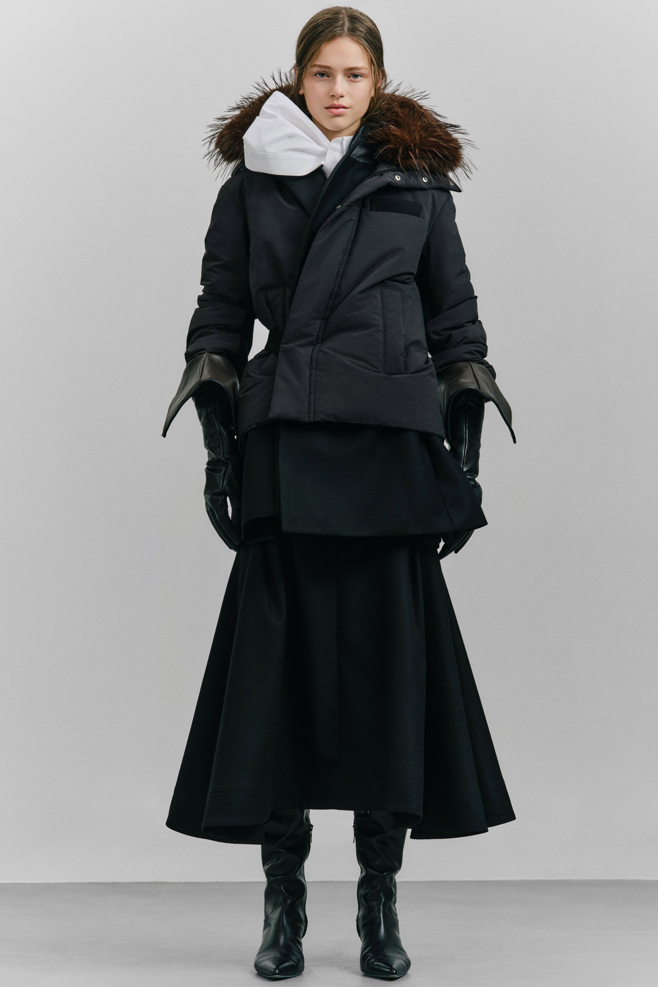 Sacai 本季继续以混合结构著称：羽绒服与西装外套、羊羔毛夹克与功能口袋结构交织在一起，打造层次丰富的机能时装。深色调与厚重面料让整体视觉更稳重，同时保持品牌标志性的结构拼接-顽石频道趋势研究